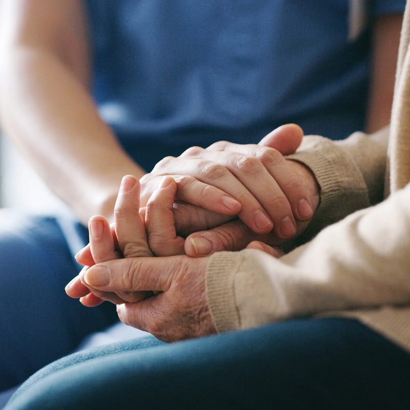 Home care nurse holding the hand of patient