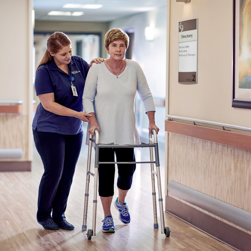 Woman being assisted walking with a walker